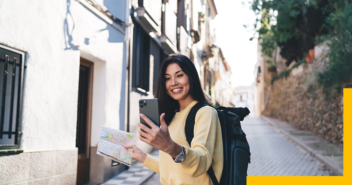 How to Become a Travel Influencer, girl taking a selfie with map in hand and wearing a backpack on the narrow street.