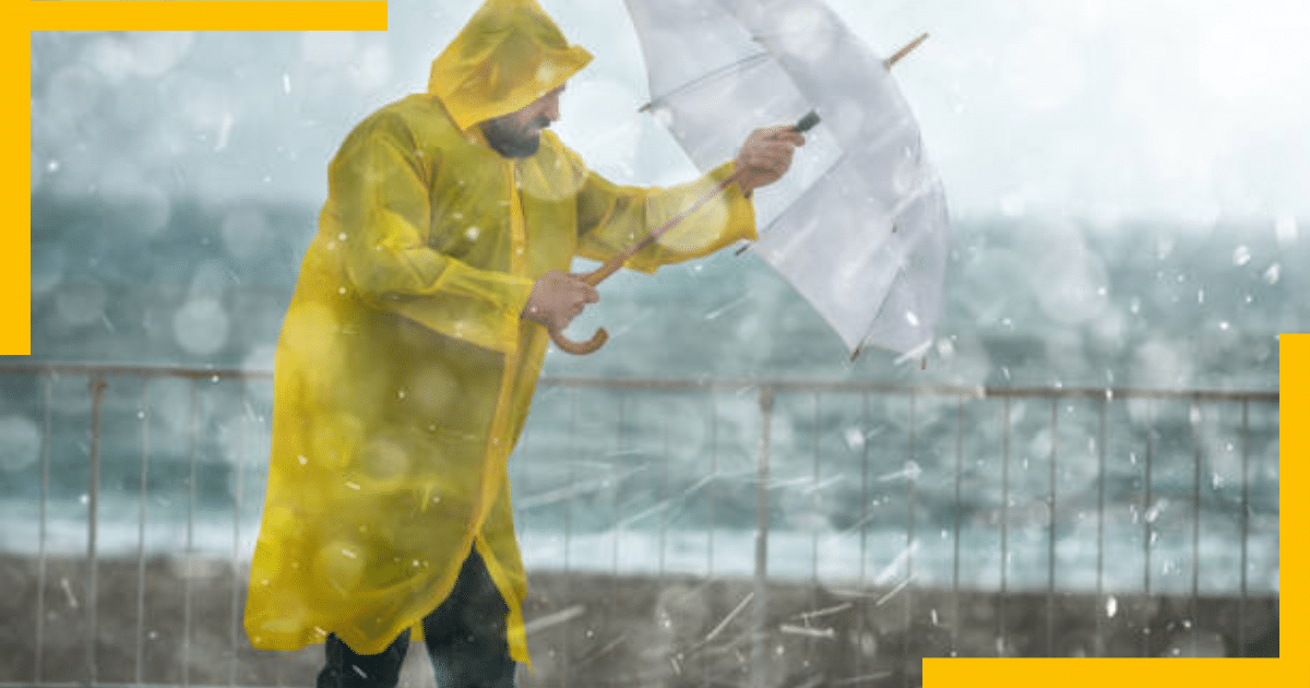 A man wearing raincoat and holding an umbrella