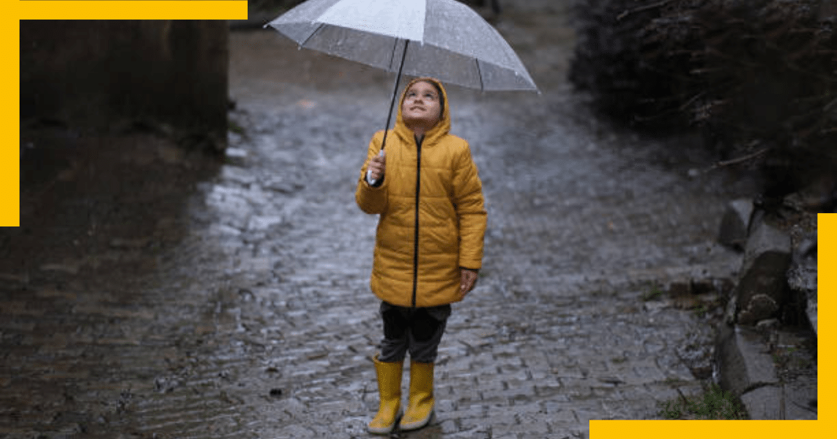 A girl wearing a raincoat and holding umbrella