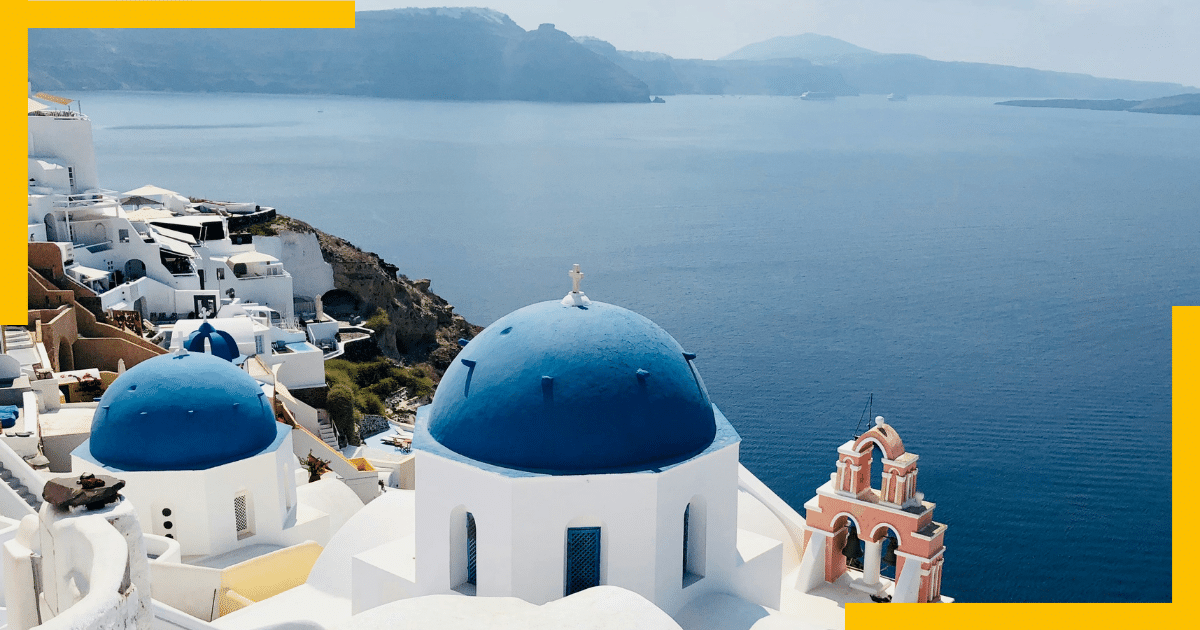 The iconic blue domes of Santorini with white buildings and Aegean Sea 